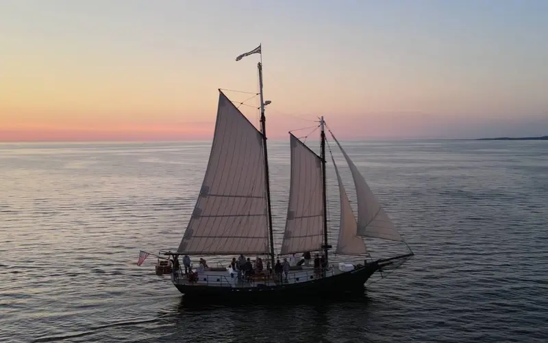 Schooner Serenity in silhouette against a pink and orange sunset